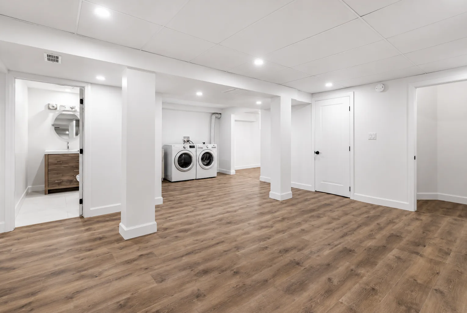 Finished lower level with wood-look flooring, recessed lighting, a laundry area and a full bathroom