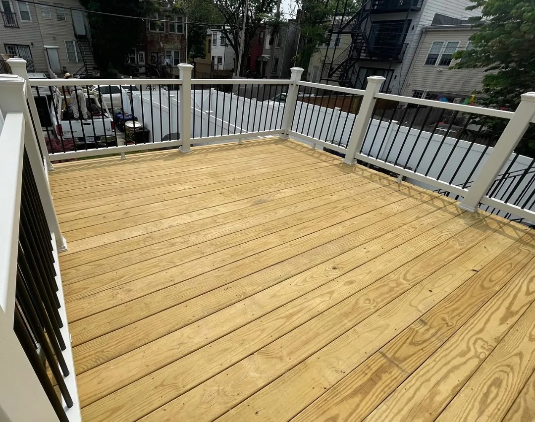 Wood deck with white and black railings behind a row house