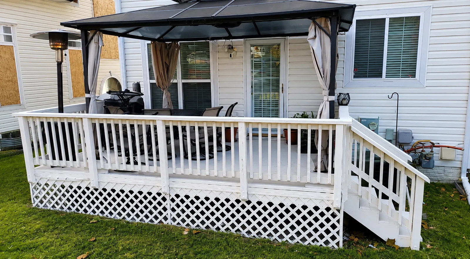 Rear deck with white railings, a covered seating area and a stair run down to the yard