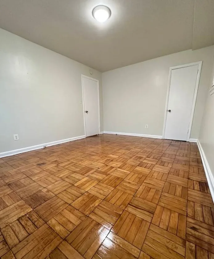 Empty room with original parquet wood flooring and painted trim in an older house