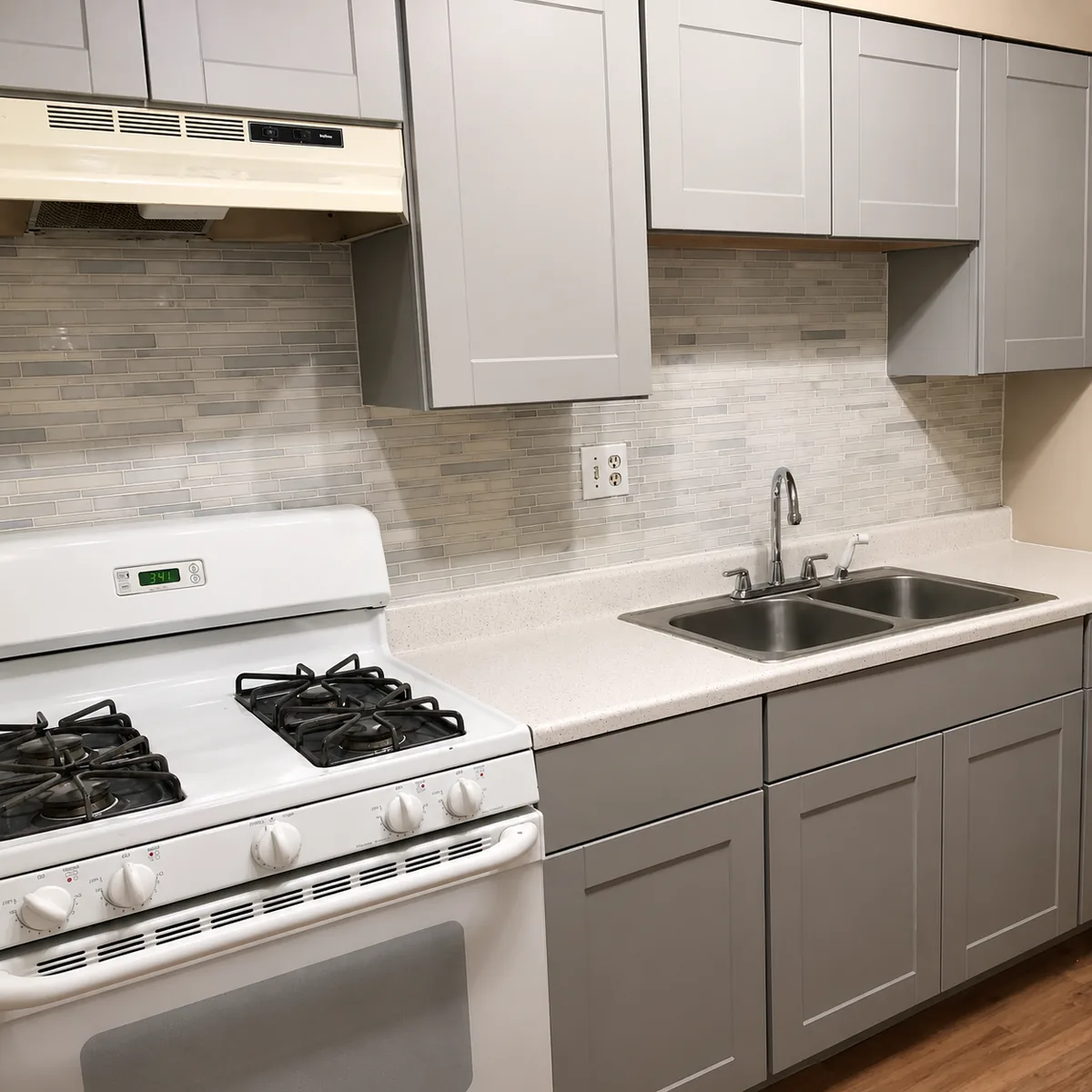 Galley kitchen with gray shaker cabinets, a tile backsplash and a light countertop